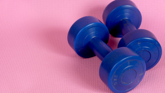 Two royal blue dumbells on a bright pink background.