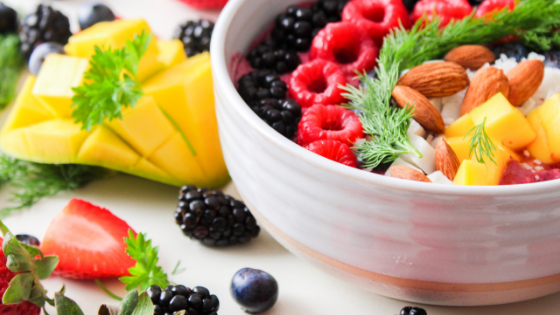 Smoothie bowl topped with fruit and nuts in a white bowl with fruit on the outside.