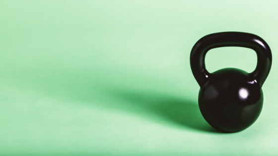 Black kettlebell on a mint green background.