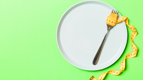 White pate with a silver fork wrapped in a yellow tape measure on a lime green background.