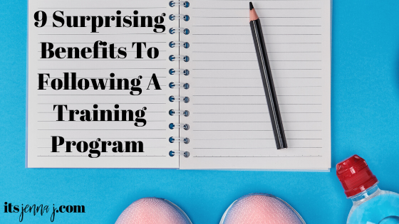 White notebook on bright blue background with the very tips of pink sneakers and a bottle of water. "9 Surprising Benefits To Following A Training Program" 