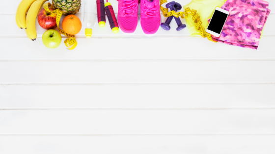 A white background with a line of colorful "wellness" stuff along the top. Fruit, a jump rope, sneakers, dumbbells, a phone, and yoga pants.