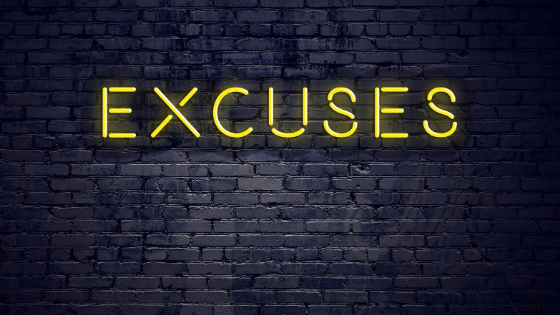 Black brick wall with "excuses" illuminated in yellow neon light.