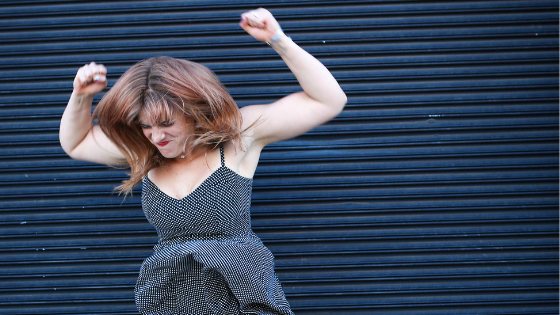 Girl in a black and white polka dot dress looking very angry against a black background.