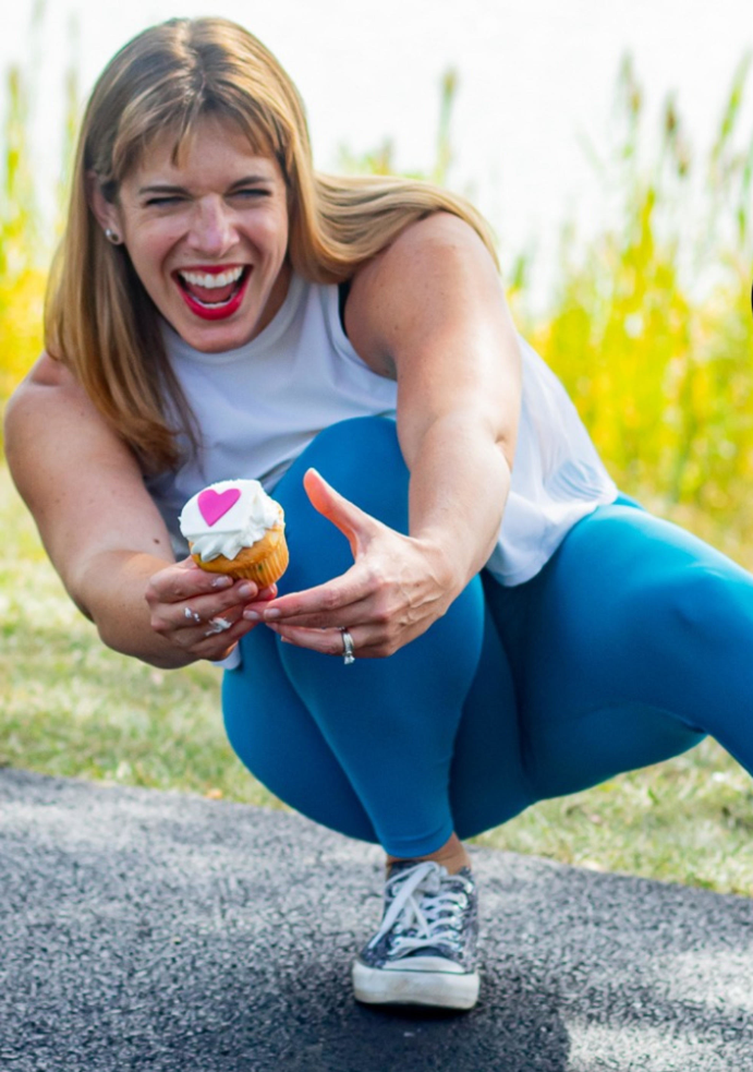 Jenna crouching down holding a cupcake