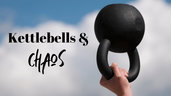 A blue sky with white clouds are in the background. A hand holds a kettlebell upside down. The words "Kettlebells & Chaos" are to the left in black text.